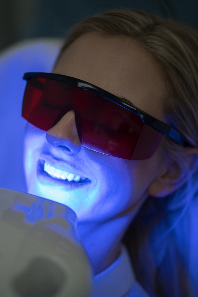 Patient undergoing professional LED teeth whitening with protective red glasses at Yonge Forest Dental in Barrie.