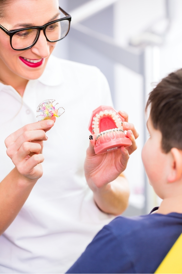 Dentist at Yonge Forest Dental in Barrie showing a young patient how an orthodontic appliance works using a dental model